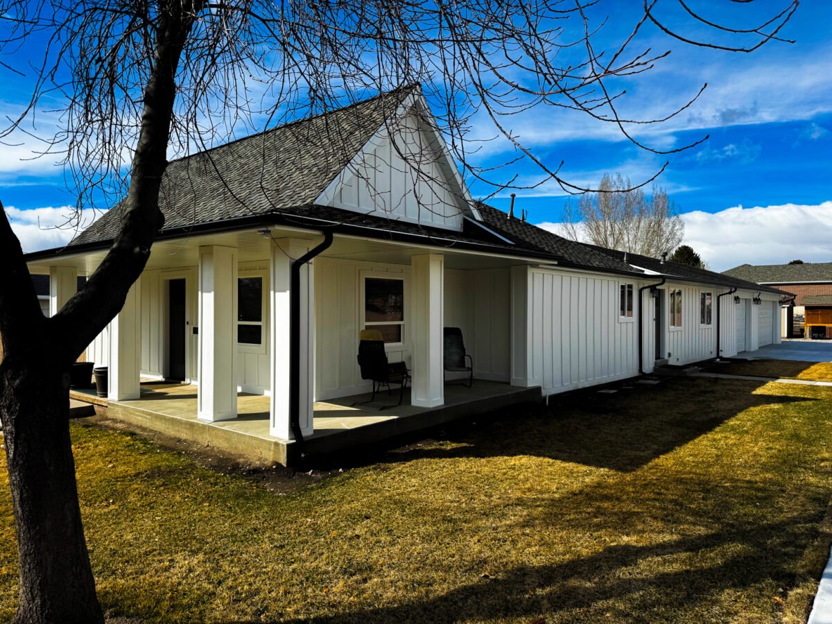 A luxury custom home exterior featuring a spacious covered porch with high ceilings, recessed lighting, and elegant stone pillar accents.
